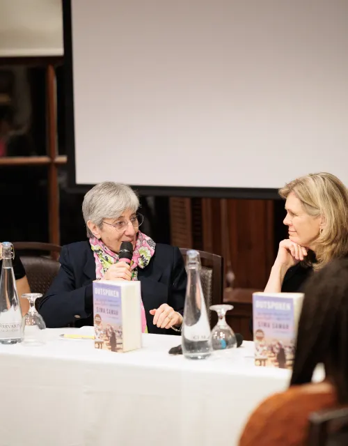 Panel of four women seated at a table with microphones and books, engaged in a discussion.