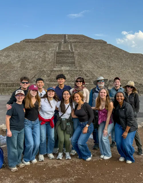 A group of students smiling in front of pyramids of Teotihuacan in Mexico.