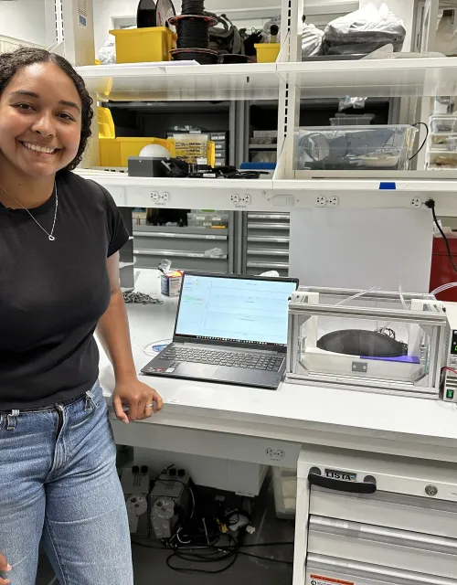 Senior Tiahna Padilla in the lab standing next to her thesis project.