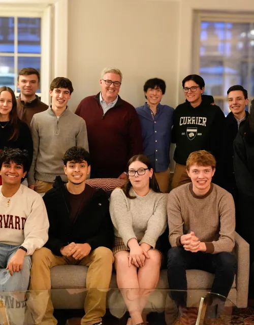Large group of students and adults pose together in a living room.