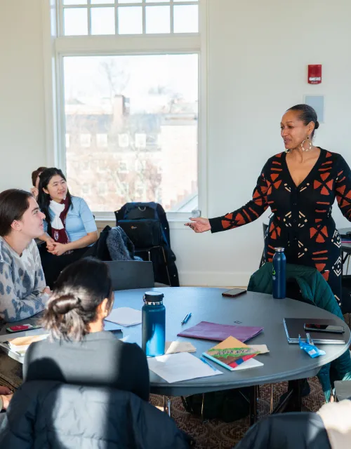 Reverand Mariama standing in the front of the room speaking to the students.