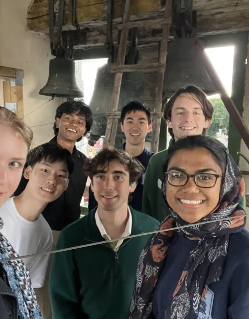 Seven members of the Lowell Bellringers huddled in for a picture together at the top of a belltower in Europe.