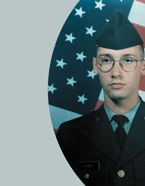 Cory Garbe in his military uniform against a gray background and backdrop of the American flag.