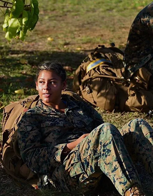 Vanessa Valverde '27 dressed in her uniform, sitting on the ground and staring off into the distance, during her time serving in the Marine Corps.