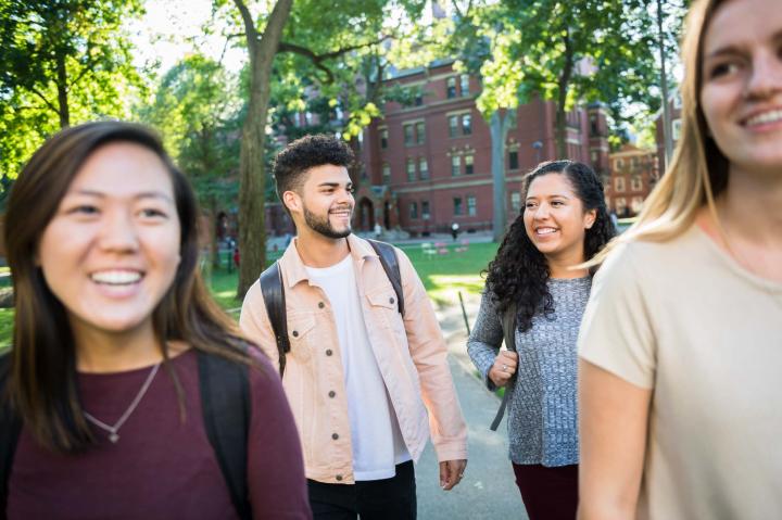 Four students smiling and walking through campus