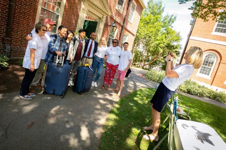 Dean of Students Katie O’Dair photographs newcomer David Zhang (center with hat) as he poses with Adele Fleet Bacow, Harvard President Larry Bacow, and Senior Assistant Dean of Residential Life and First-Year Students Nekesa Straker. 