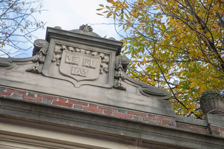 The Veritas shield engraved on one of the gates around Harvard Yard