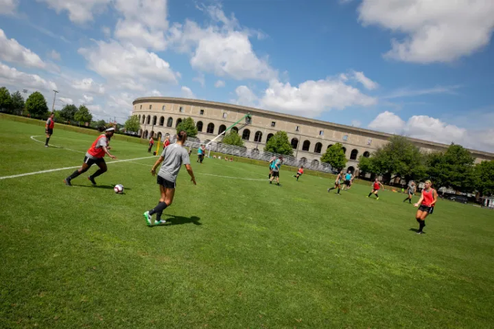 Members of the Harvard community playing soccer outside of Harvard Stadium.