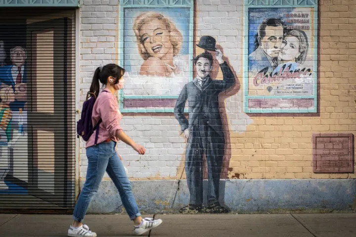 A pedestrian walks past a painted Charlie Chaplin on the Church Street mural.