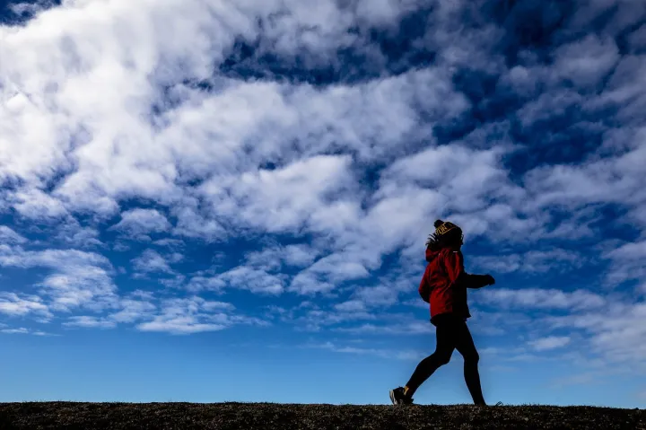 A runner jogs in a field.