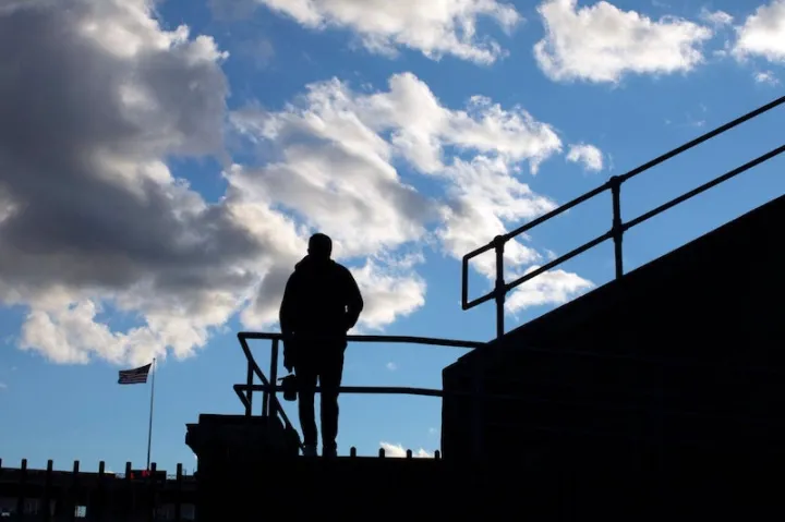 Student athlete stares out onto the football field on the stadium steps.