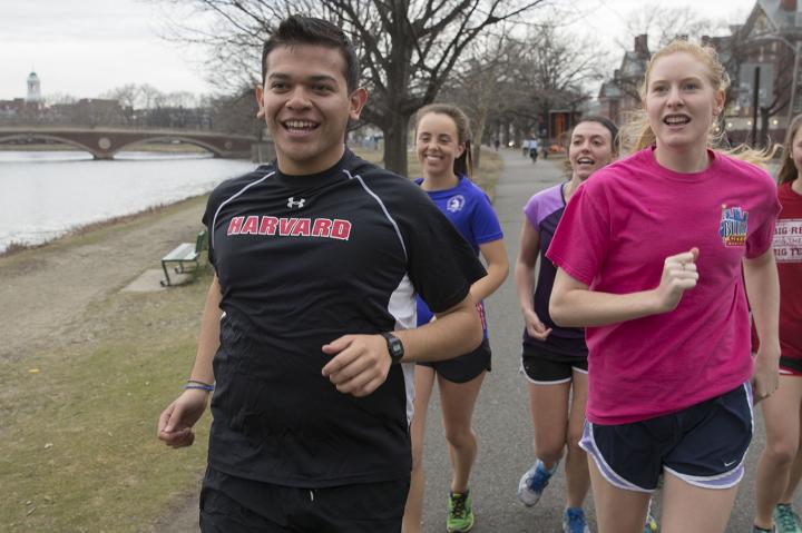 students running along the Charles River