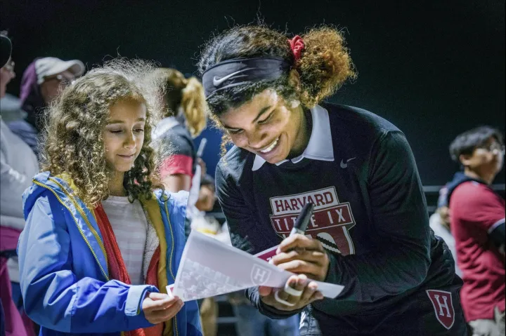 A student-athlete signs a fan's poster.