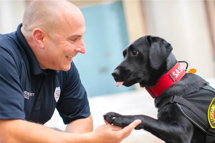 Sasha offers a paw to her handler, Officer Steven Fumicello.