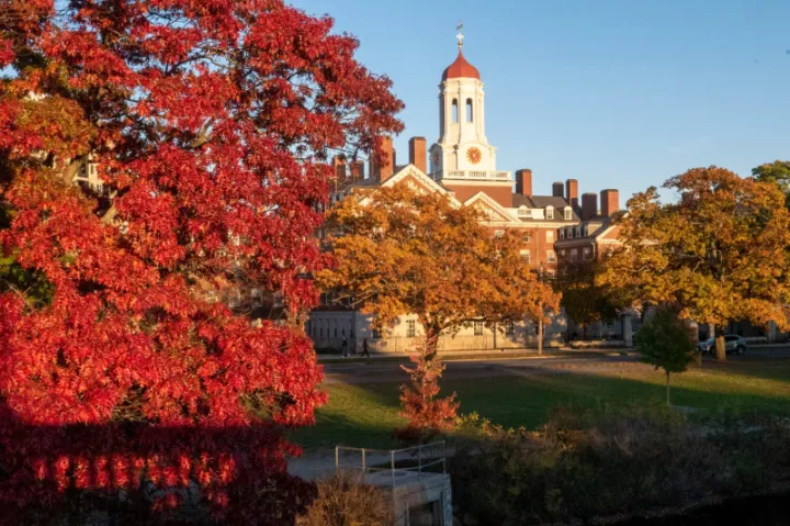 Photo of Dunster House from across the river with beautiful fall colored trees in the frontground. 