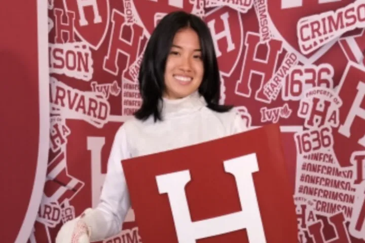 Cynthia Liu posing with Harvard crest in fencing uniform