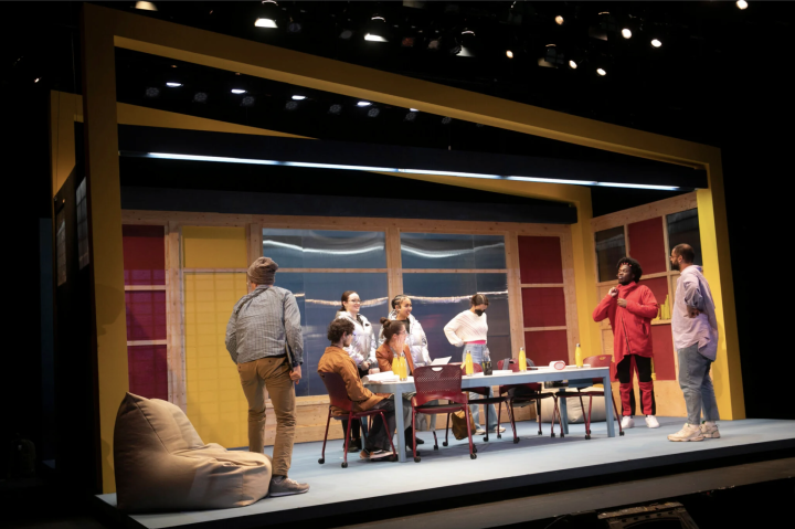 Actor sitting around a table onstage for "The Singularity Play"