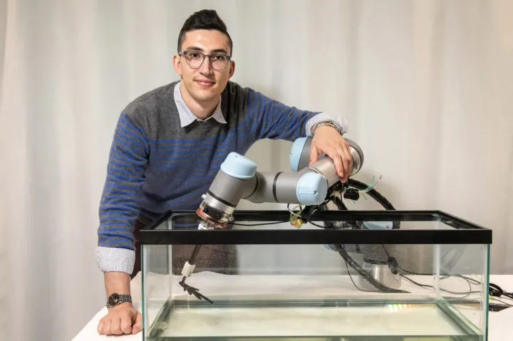 Henry Cerbone standing behind his robotic model of a basilisk lizard’s broad foot