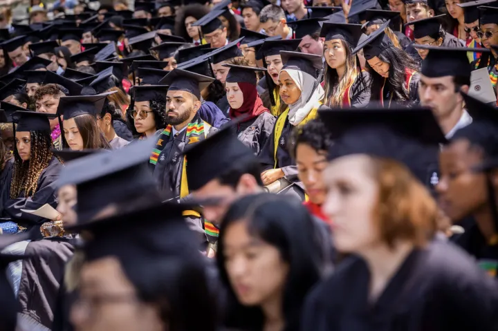 graduates in caps and gowns in seats on commencemnent