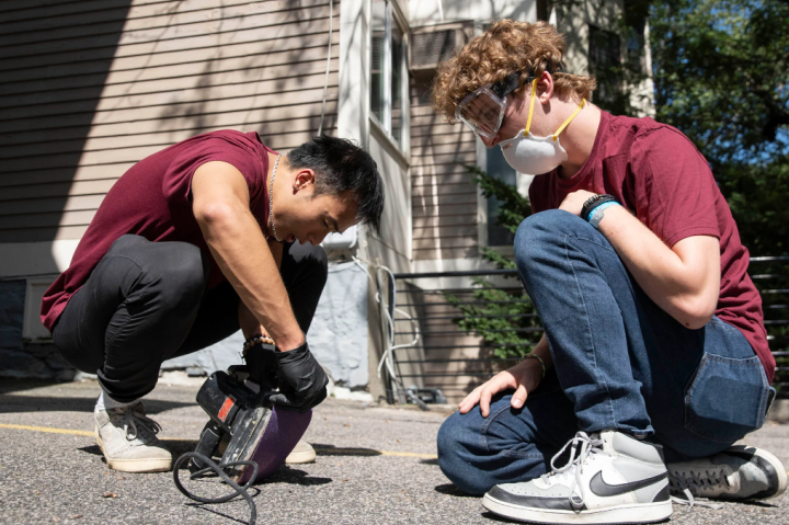 Xuanthe Nguyen ’25 (left) and Luke Blanchette ’27 prep the sander before they tackle fences at the historic Harriet Jacobs House in Cambridge.