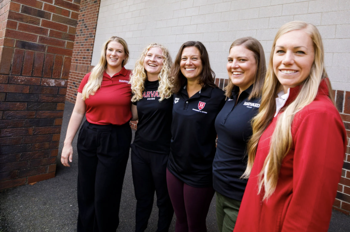 5 women lined up next to each other in front of a building dressed in athletic gear