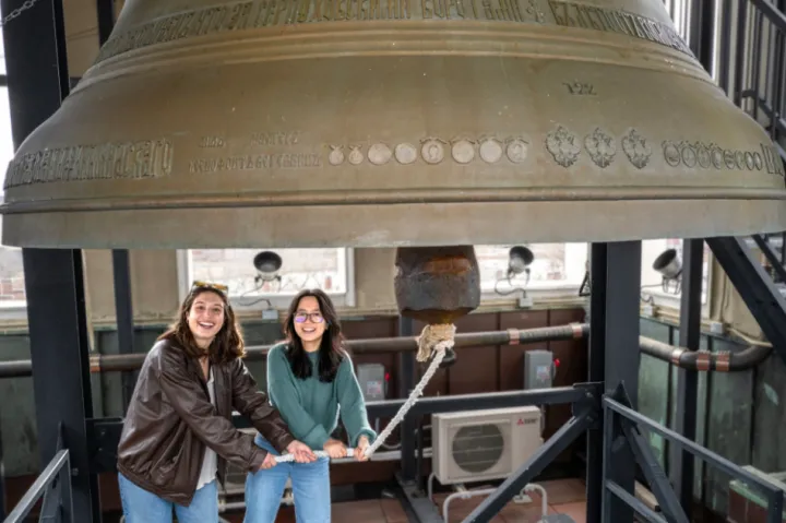 Sofia Giannuzzi (left) and Linh Vu ring a large bell in the Lowell House bell tower as part of a Sunday House tradition.