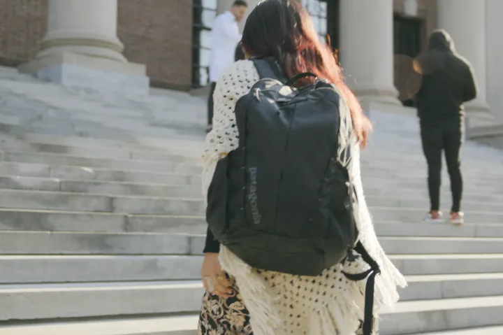 Female student wearing backup walking up Widener steps
