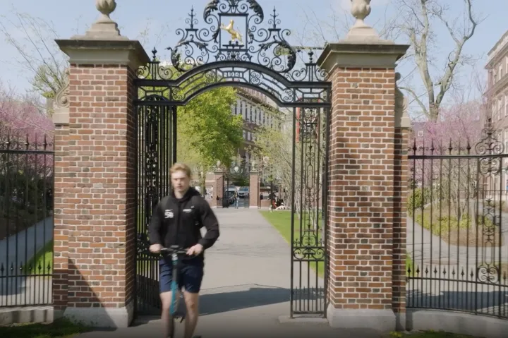 Student on scooter exits Harvard gate