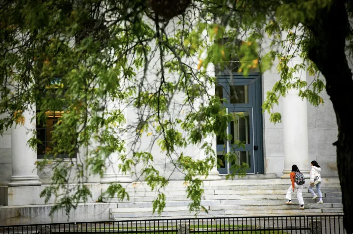 Students walk up set of stairs outside building