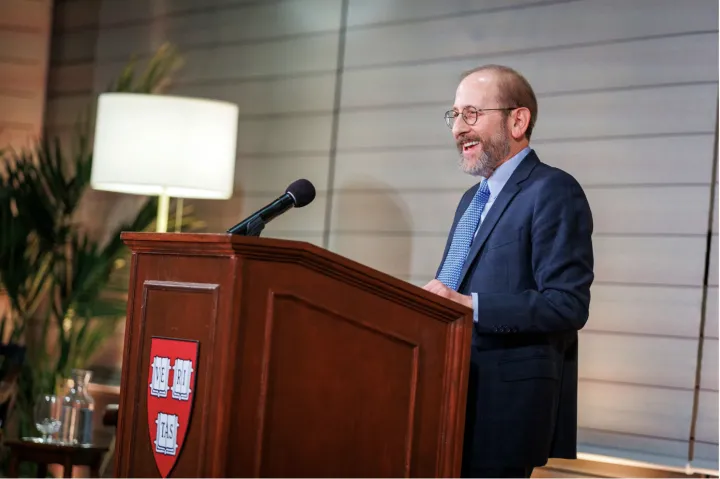Alan Garber stands behind a podium with the Harvard Shield