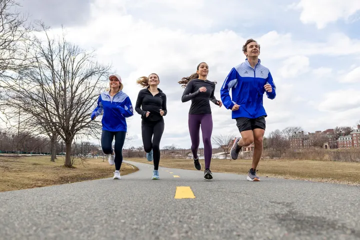Four people jogging on a paved path outdoors.