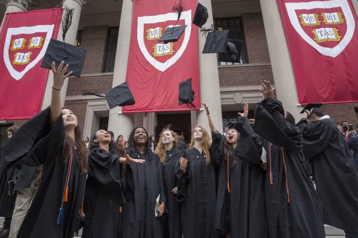 Graduates in gowns celebrate by tossing caps in the air