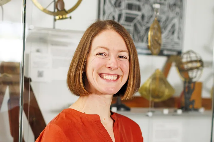 Hannah Marcus smiles in a bright red top at the Collection of Historical Scientific Instruments. 