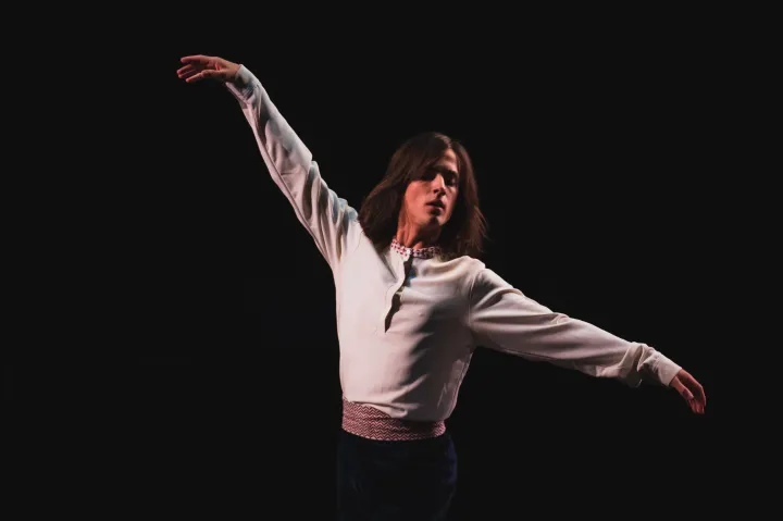 Person performing a dance on stage with arms outstretched.