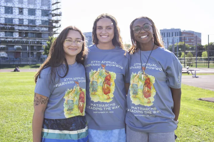 Three Harvard College students smile together while wearing Powwow 2025 t-shirts.