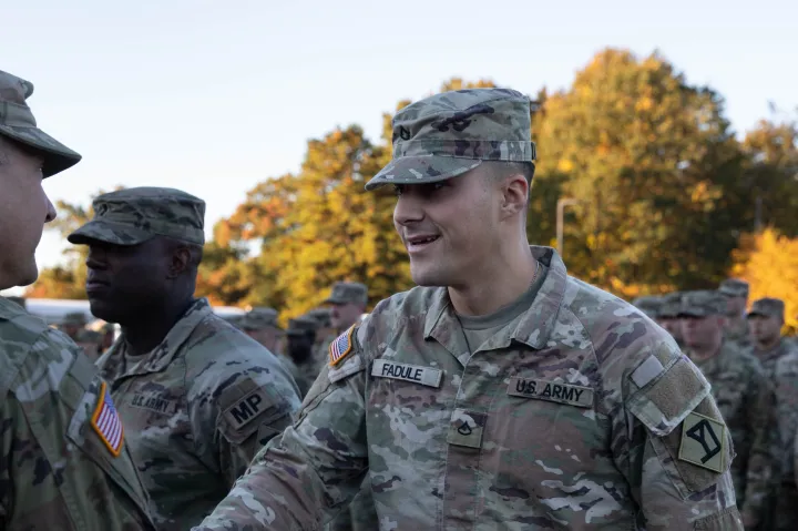 Dressed in his camoflauge uniform, Fadule smiles and shakes the hand of a fellow serviceman as he receives an award. 