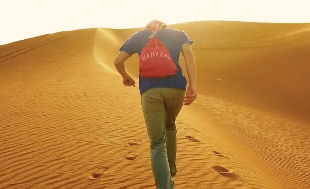 Student with Harvard backpack in desert