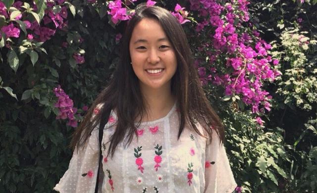 Student standing in front of flowers.