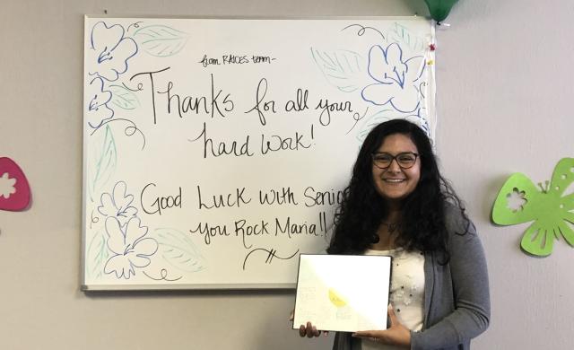 Maria posing in front of a farewell message at the end of her internship. 