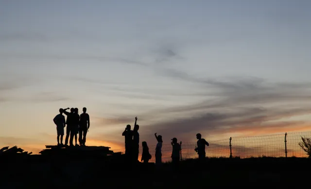 Silhouette of a group of people against a sunset background