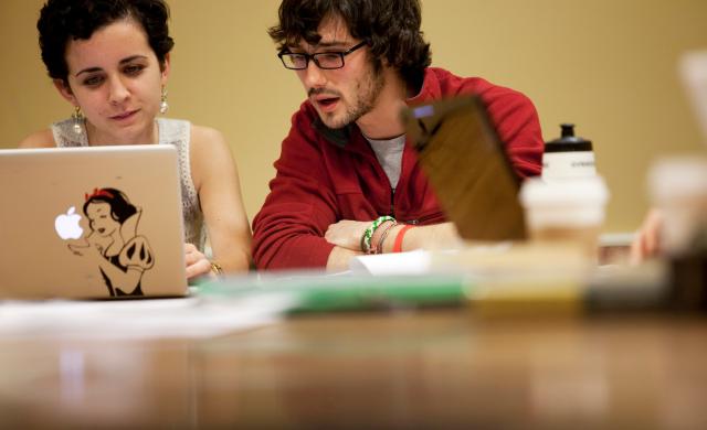 Two students sharing a laptop and speaking to one another