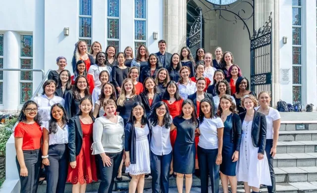 Members of the Radcliffe Choral Society standing on the steps of a church, in formal concert wear.