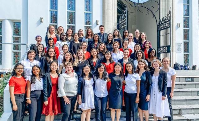 Members of the Radcliffe Choral Society standing on the steps of a church, in formal concert wear.