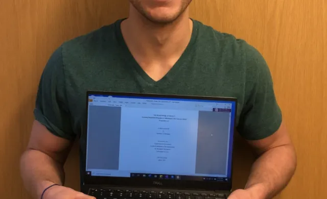 Student Holding a laptop in front of him