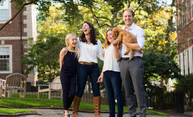 A portrait of Janine Santimauro and David Deming, faculty deans of Kirkland House, with their two daughters and dog.