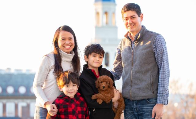 A portrait of Leslie Duhaylongsod and Eric Beerbohm, faculty deans of Quincy House, with their two sons and dog.