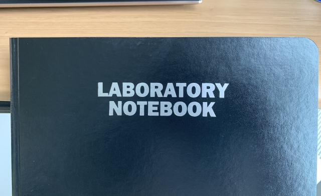 A black notebook with the words "LABORATORY NOTEBOOK" in white at the center.