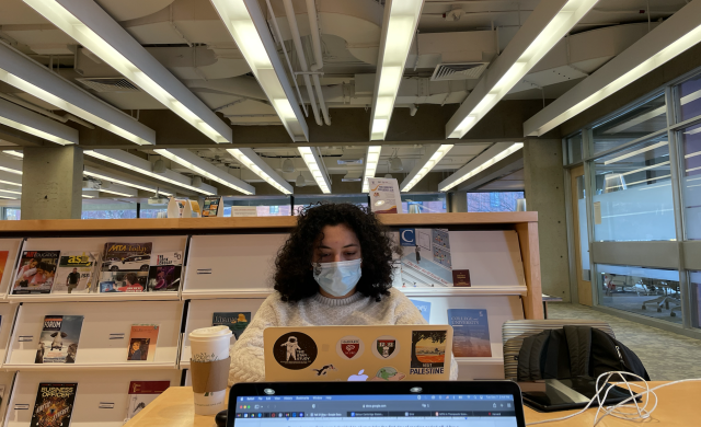 Student typing on computer in a common study space
