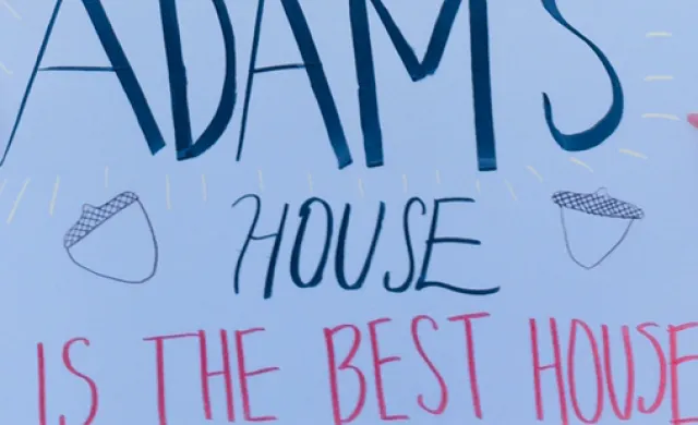 A picture of a white poster with "Adams House is the Best House" written on it.