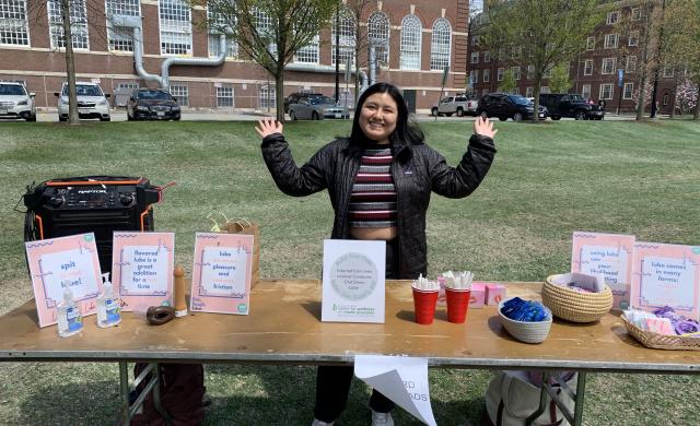A girl standing behind a table with her hands outstretched.